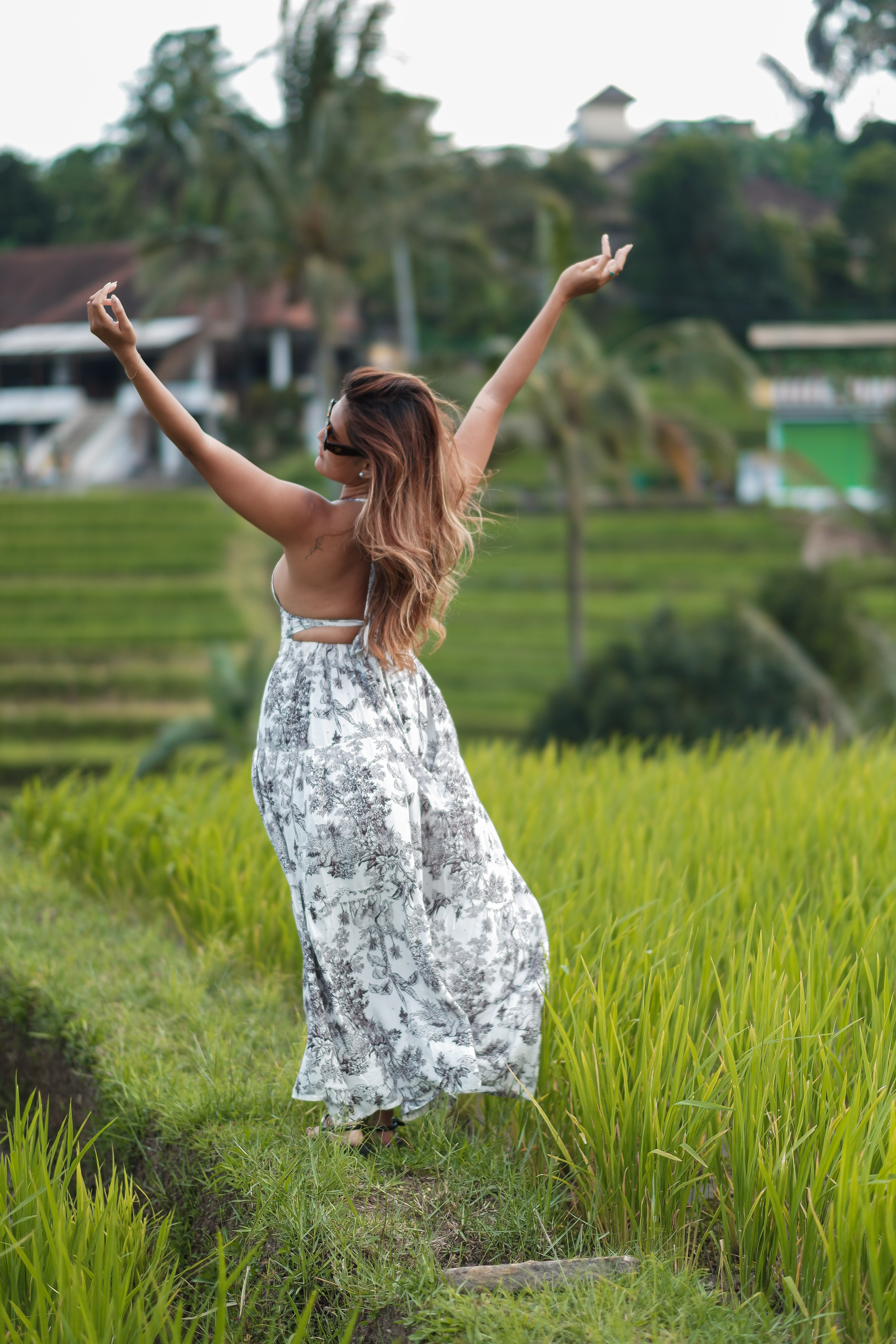 Solo traveller in flowing dress at Jatiluwih rice terraces with arms raised