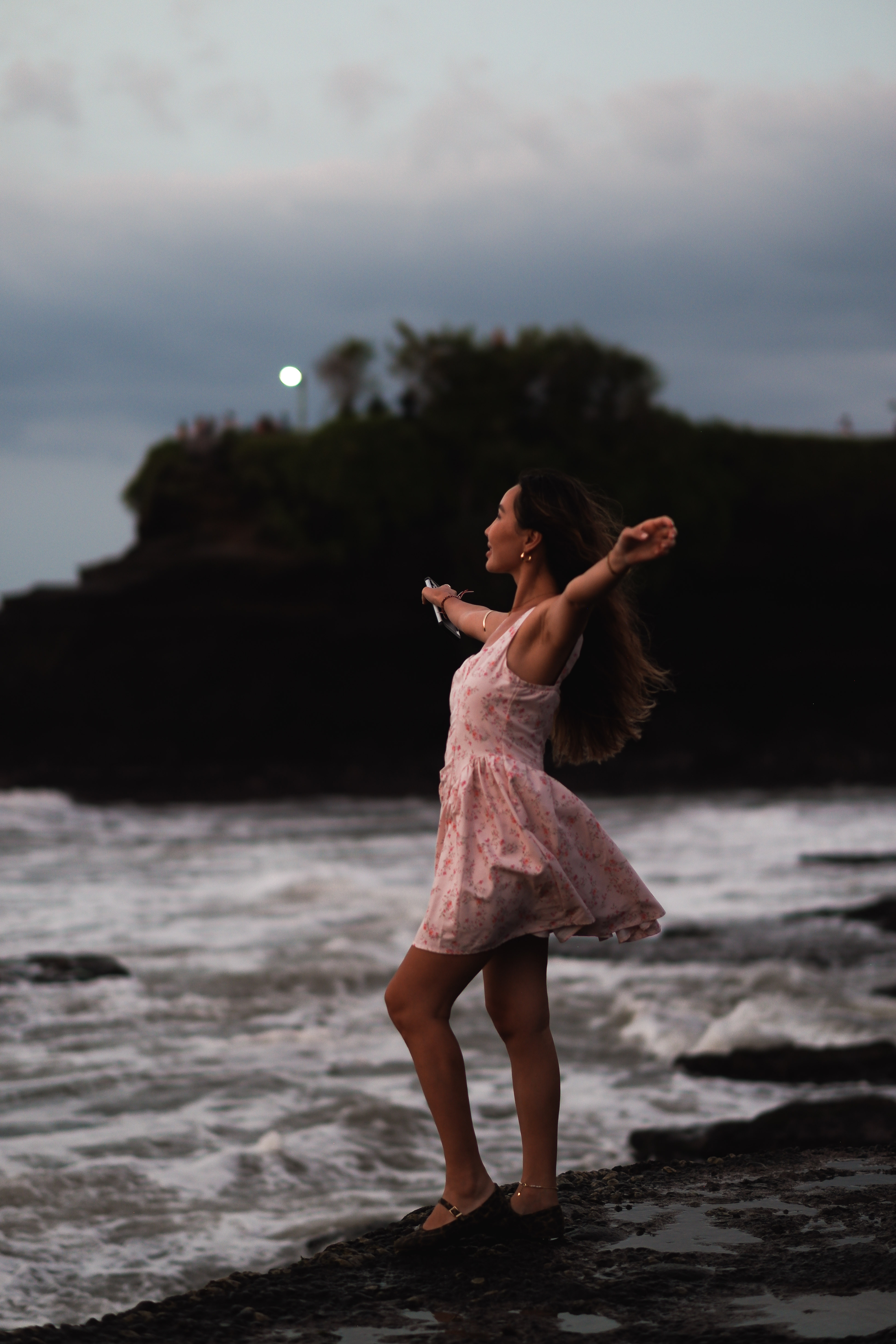 Traveller dancing on the beach at dusk near Tanah Lot at moonrise
