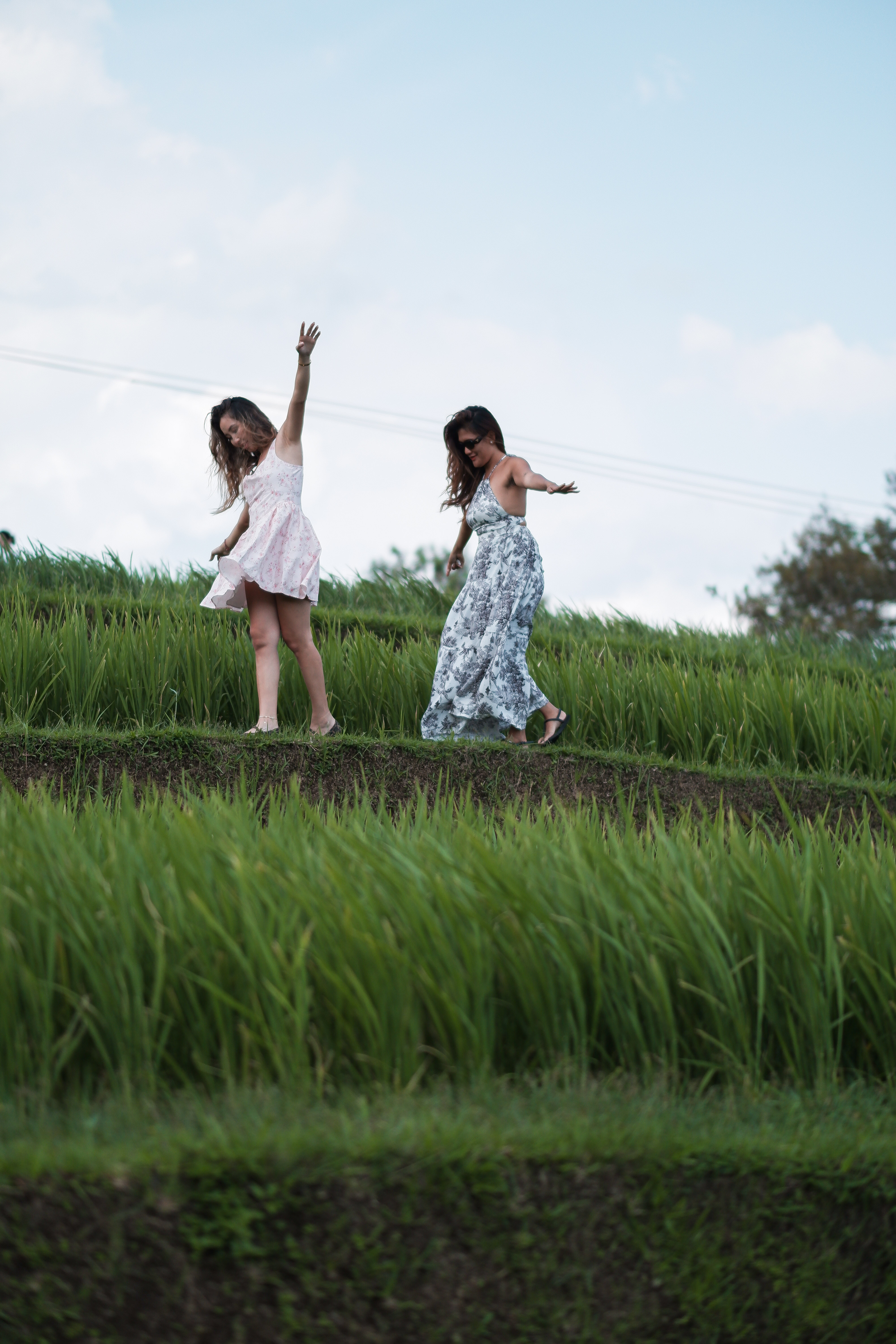 Friends walking along Jatiluwih rice terrace ridges at sunset