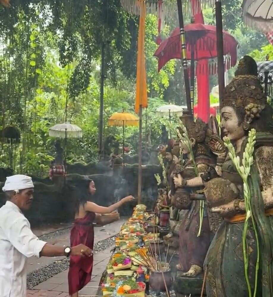Balinese priest performing a melukat purification ceremony with guest