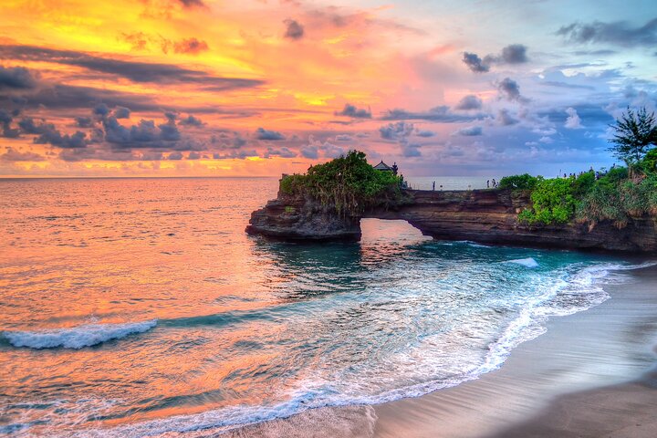 Tanah Lot temple silhouetted on its rock platform at sunset