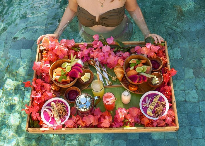 Floating breakfast tray of fruit and pastries in jungle pool