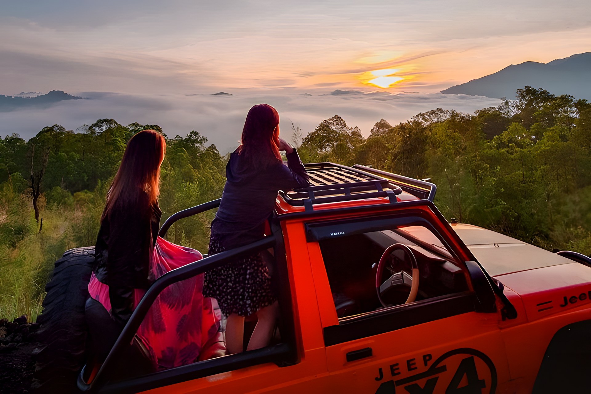 Sunrise over Mount Batur caldera with a 4x4 jeep silhouetted on the ridge
