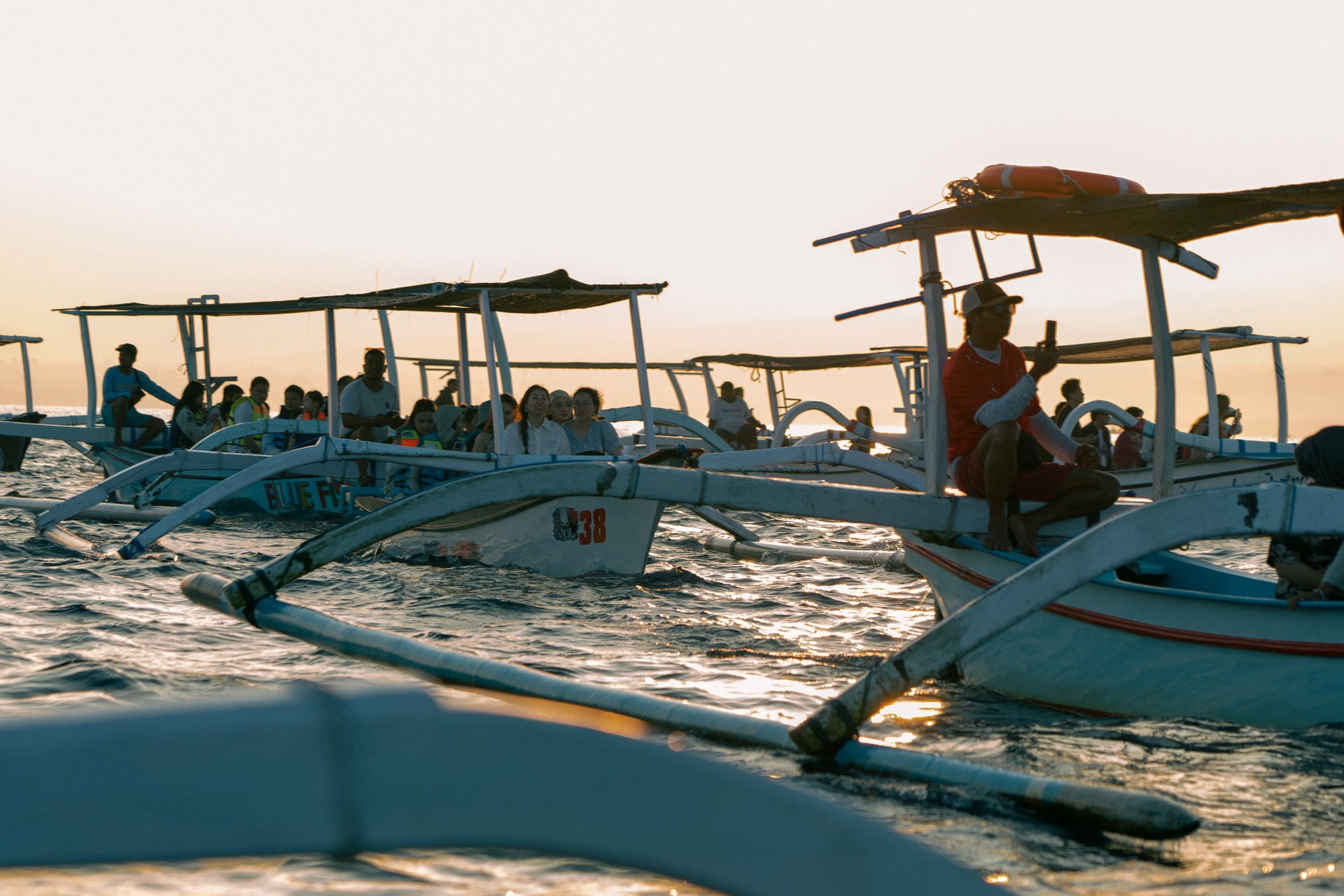 Traditional outrigger fishing boats gathered at golden-hour sunrise in Lovina, Bali for the wild dolphin watch
