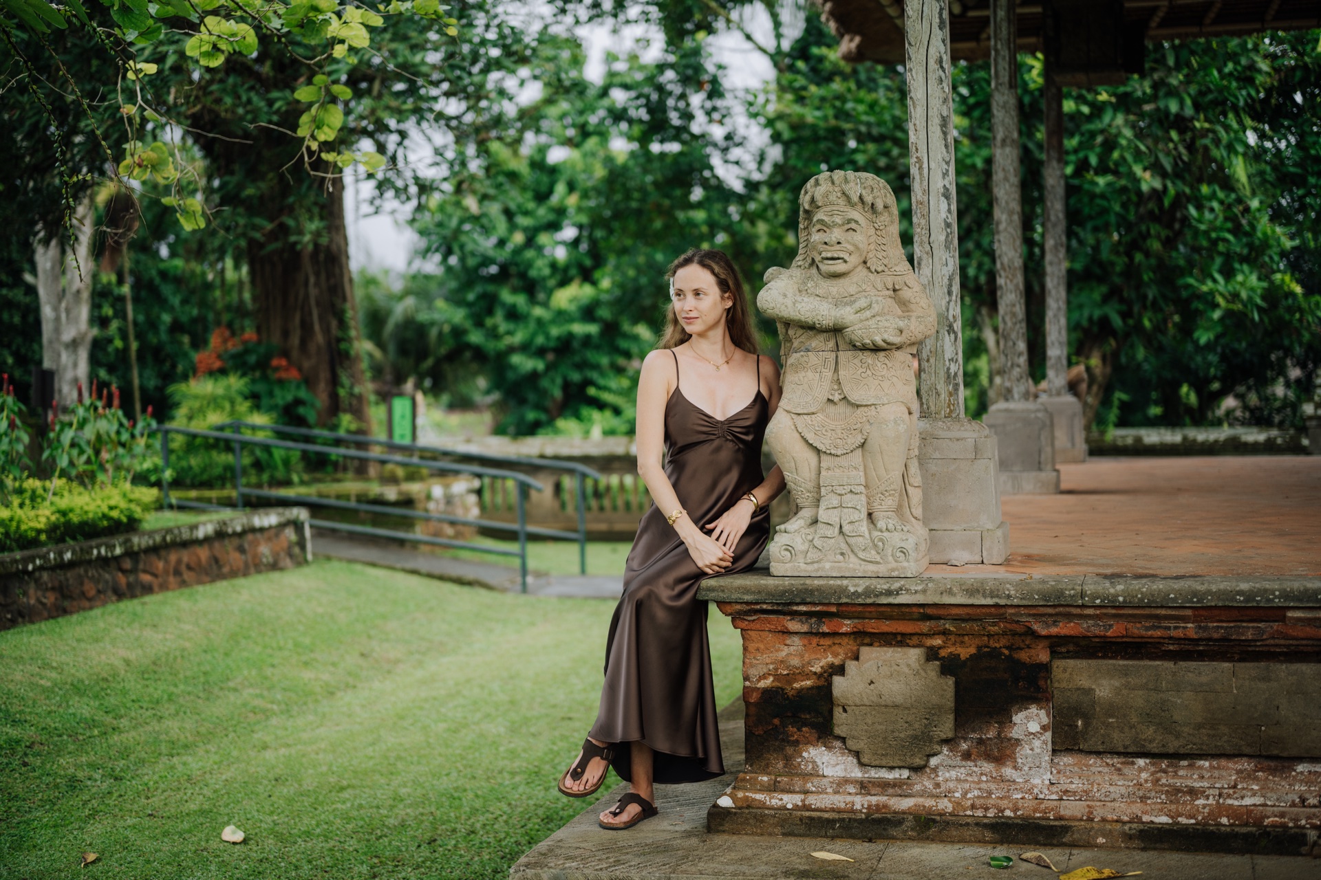 Guest receiving a melukat cleansing at Taman Beji Griya with offerings in hand