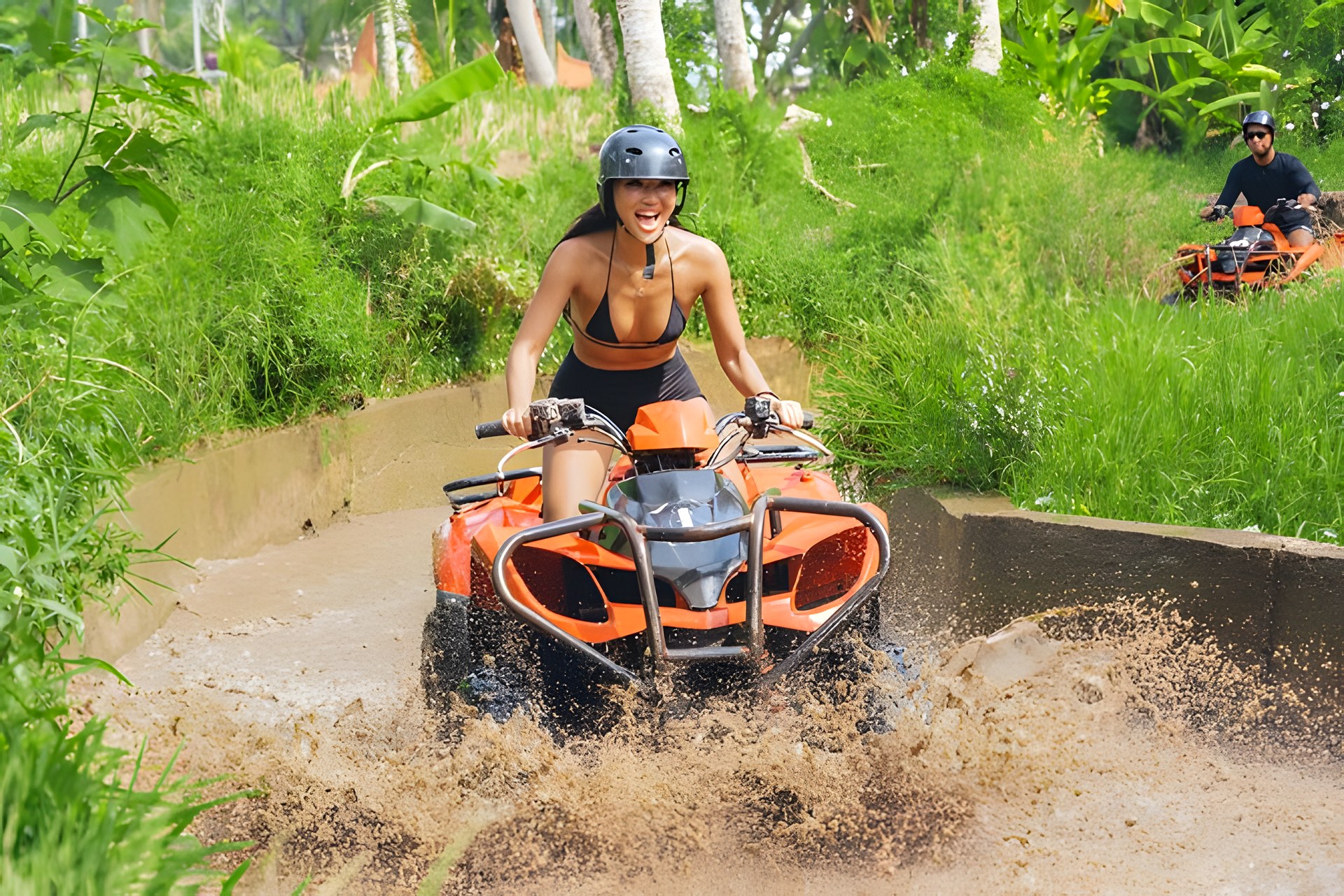 Tandem ATV riders splashing through a muddy jungle track in Singapadu, Bali